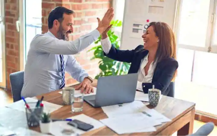 Two people high-fiving and smiling while discussing sales effectiveness