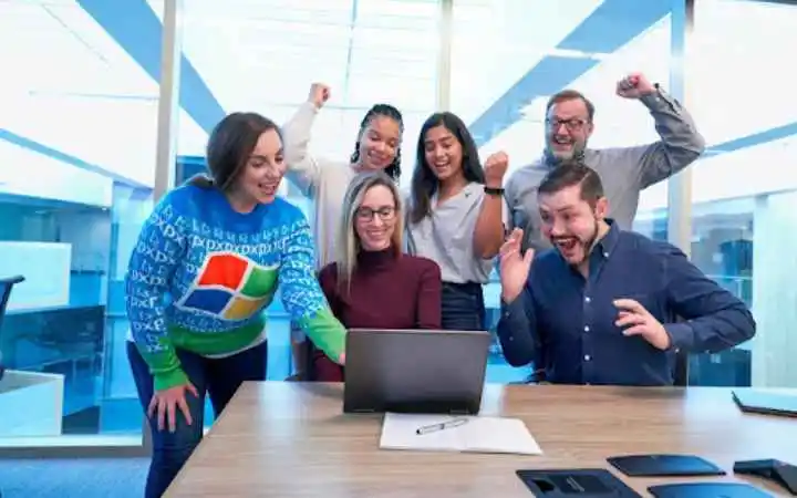 A team looking at a laptop, cheering, after improving sales effectiveness